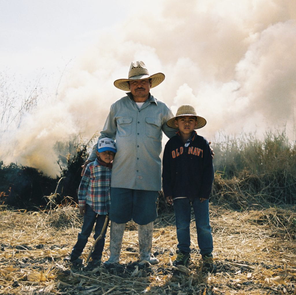 farmworker with two children looking into camera in field