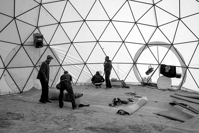 Setting up inside a newly constructed geodesic dome. Refugee Camp, Calais, France, September, 2015. Photo by Lewis Watts © Lewis Watts, 2015